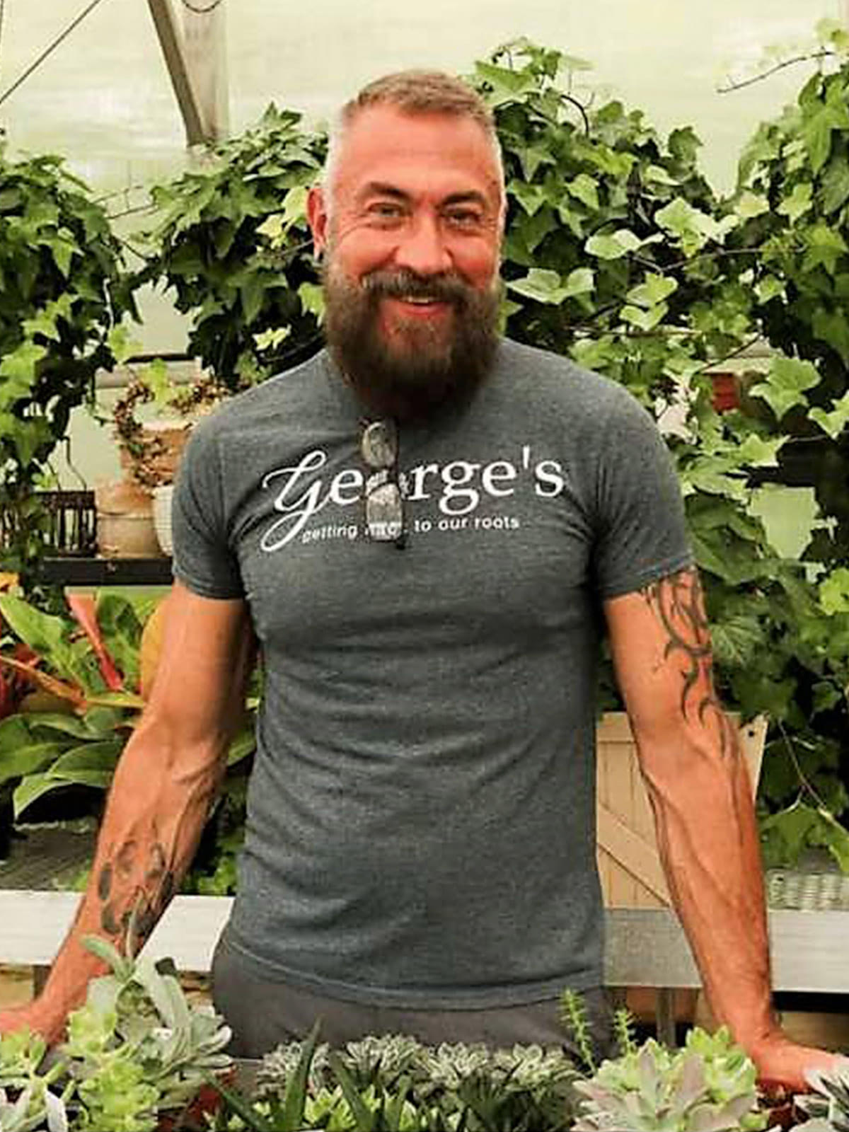 A modern photo of George, handling plants in the greenhouse