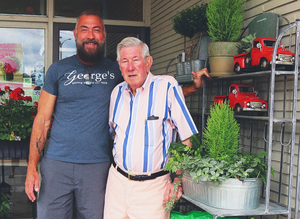 George Clement, owner of George's Flowers, poses with his father, Leroy, outside his shop's front door